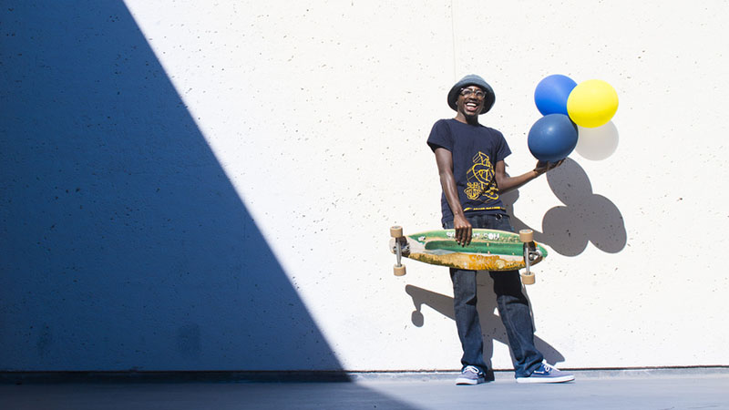 Person holding a skateboard and balloons