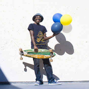 Man holding a skateboard and some balloons