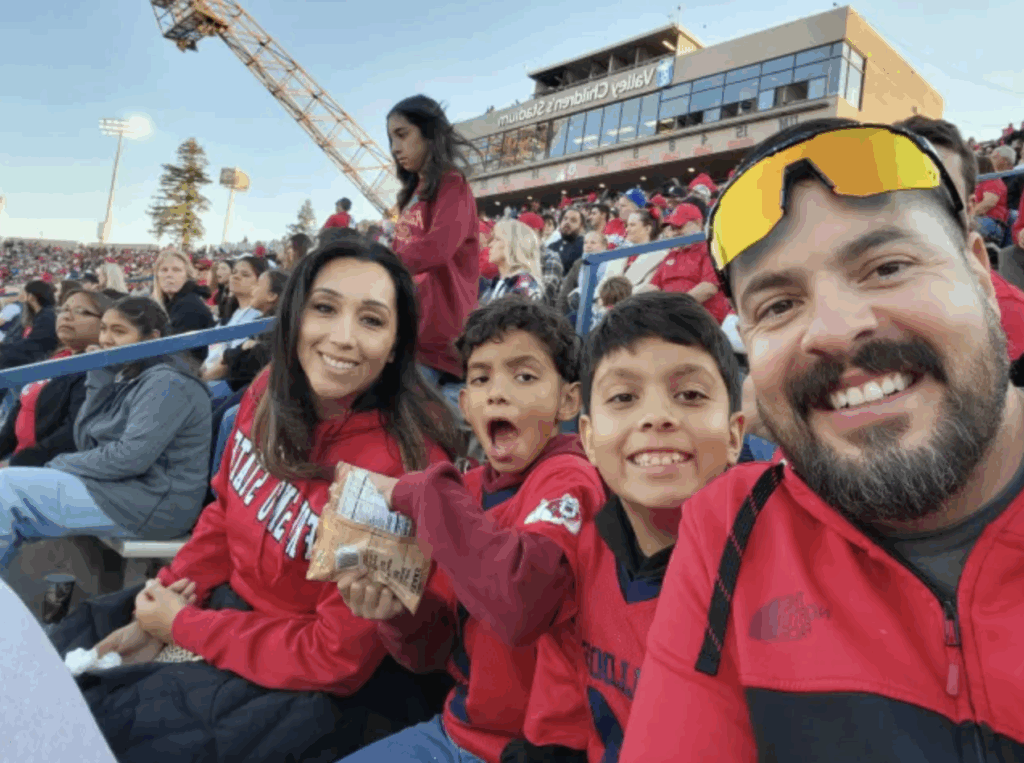 Parents and two children sitting in bleachers at a sporting event