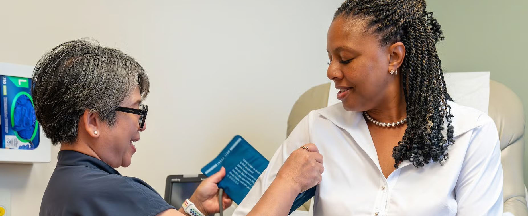 Uniformed woman checking another woman's blood pressure