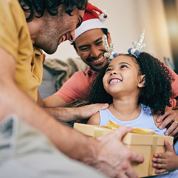 Male parents presenting young girl with a gift