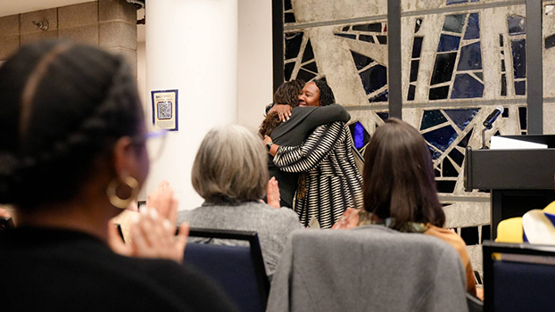 Two women hugging at the front of a conference room