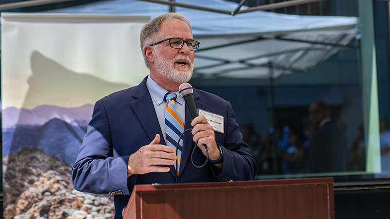 Steve speaking at a podium holding a microphone