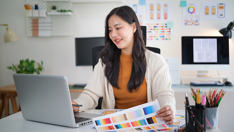 Female web designer developing mobile app layout, reviewing user interface mockups