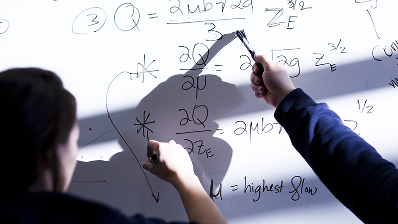 People doing math equations on a dry-erase board