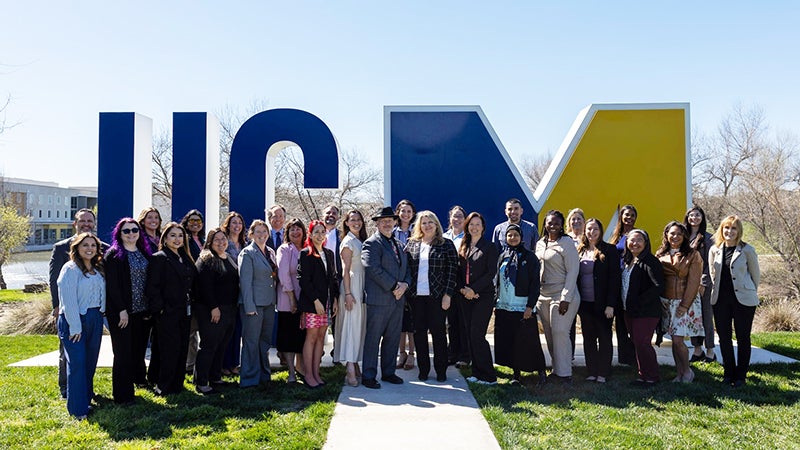 Group of people standing in front of the UC Merced Sign