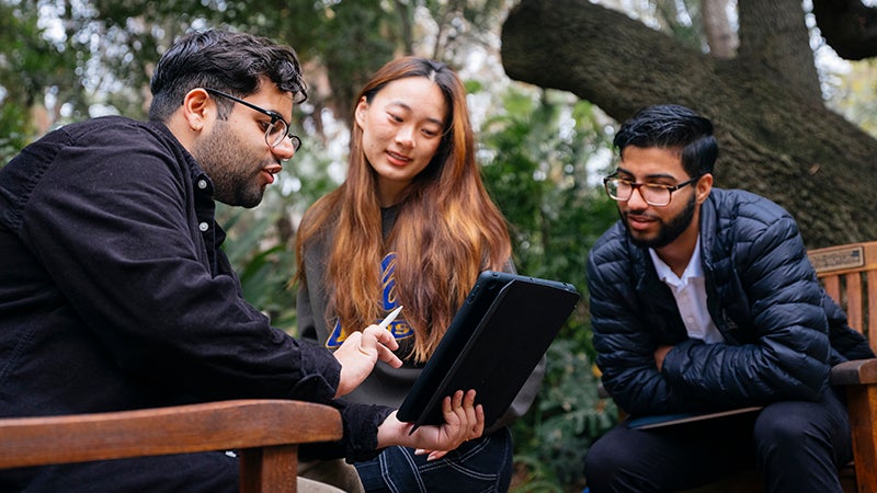 Three people working around a tablet at UCLA