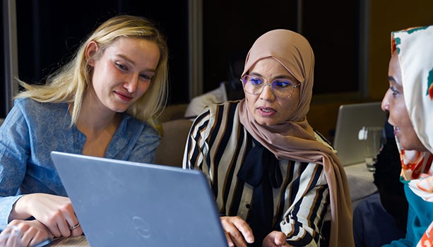 Three women working together on a laptop computer