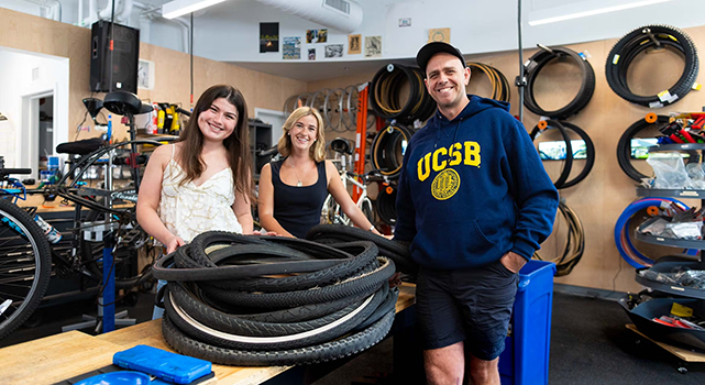 Three people standing next to stack of bike tires