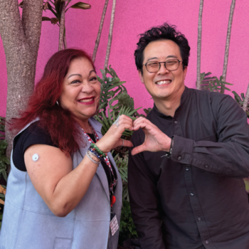 Woman and man standing next to each other, shaping a heart with their combined hands