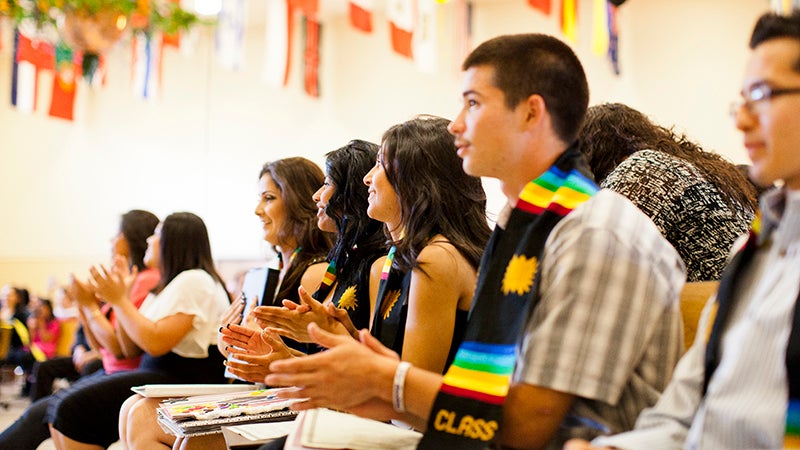 UC Puente Program at graduation celebration surrounded by international flags