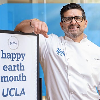 Chef leaning on "happy earth month UCLA" sign