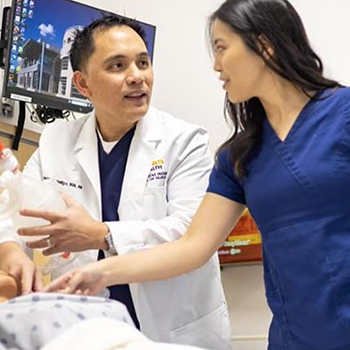 Man demonstrating nursing technique for colleagues on plastic dummy