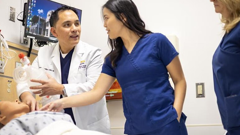 Man demonstrating nursing technique for colleagues on plastic dummy
