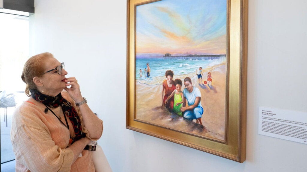 Woman standing in a hallway admiring a painting