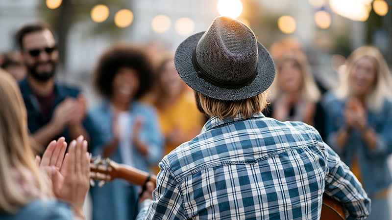 Man playing guitar, back view, with crowd facing him