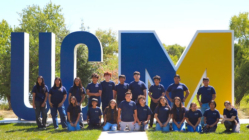 Group of students standing by the UCM sign