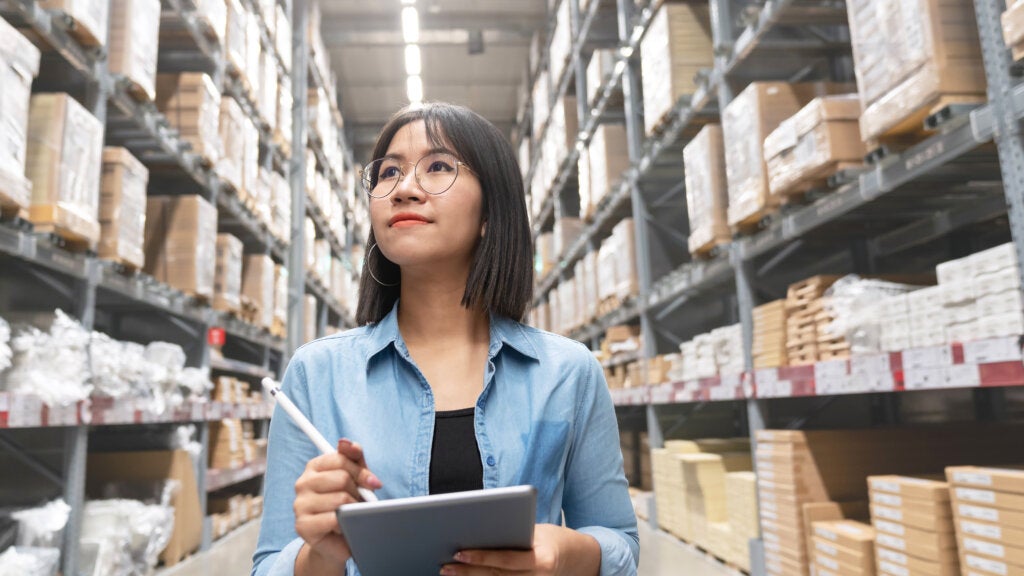 Young asian woman stocktaking inventory in a warehouse