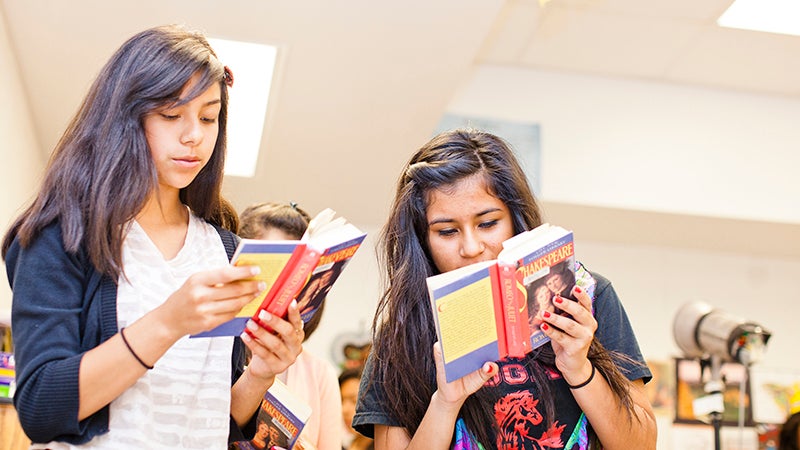 Two girls reading books in a library