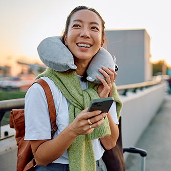 Woman traveling, smiling, holding phone at airport