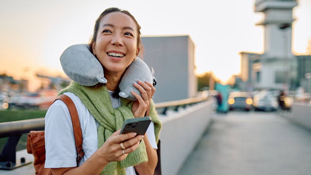 Woman traveling, smiling, holding phone at airport