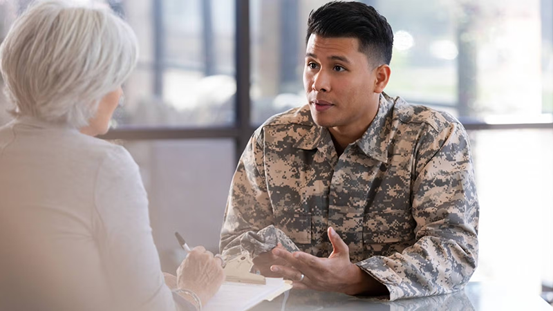 Person in Army attire speaking with medical professional