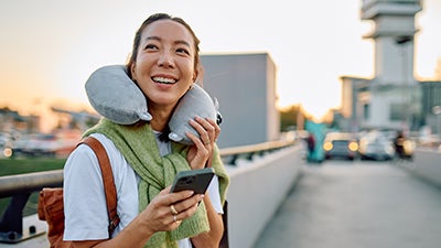 Woman traveling, smiling, holding phone at airport