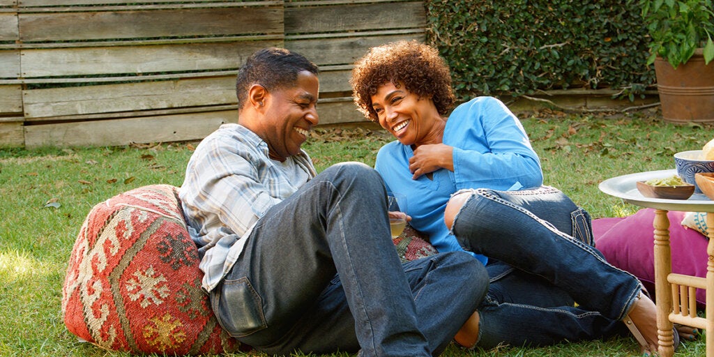 Smiling Mature Couple Enjoying Drinks And Snacks In Backyard Garden Together