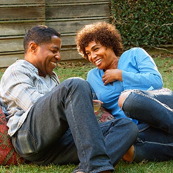 Smiling Mature Couple Enjoying Drinks And Snacks In Backyard Garden Together