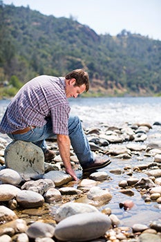 Man sitting on stones touching water