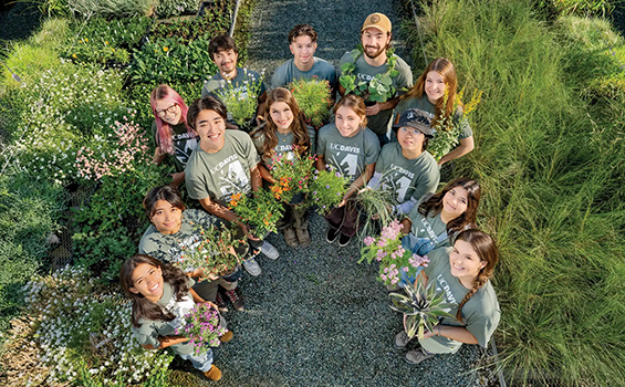 Semicircle of students holding flowers and smiling