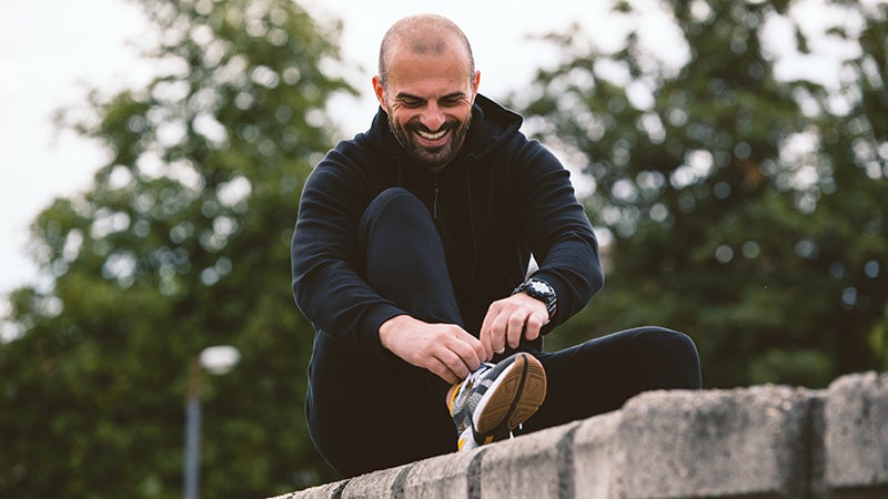Front view portrait of active, man tying his shoelaces for a run